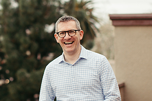 Andy Crouch is smiling looking at the camera. He is standing outside.