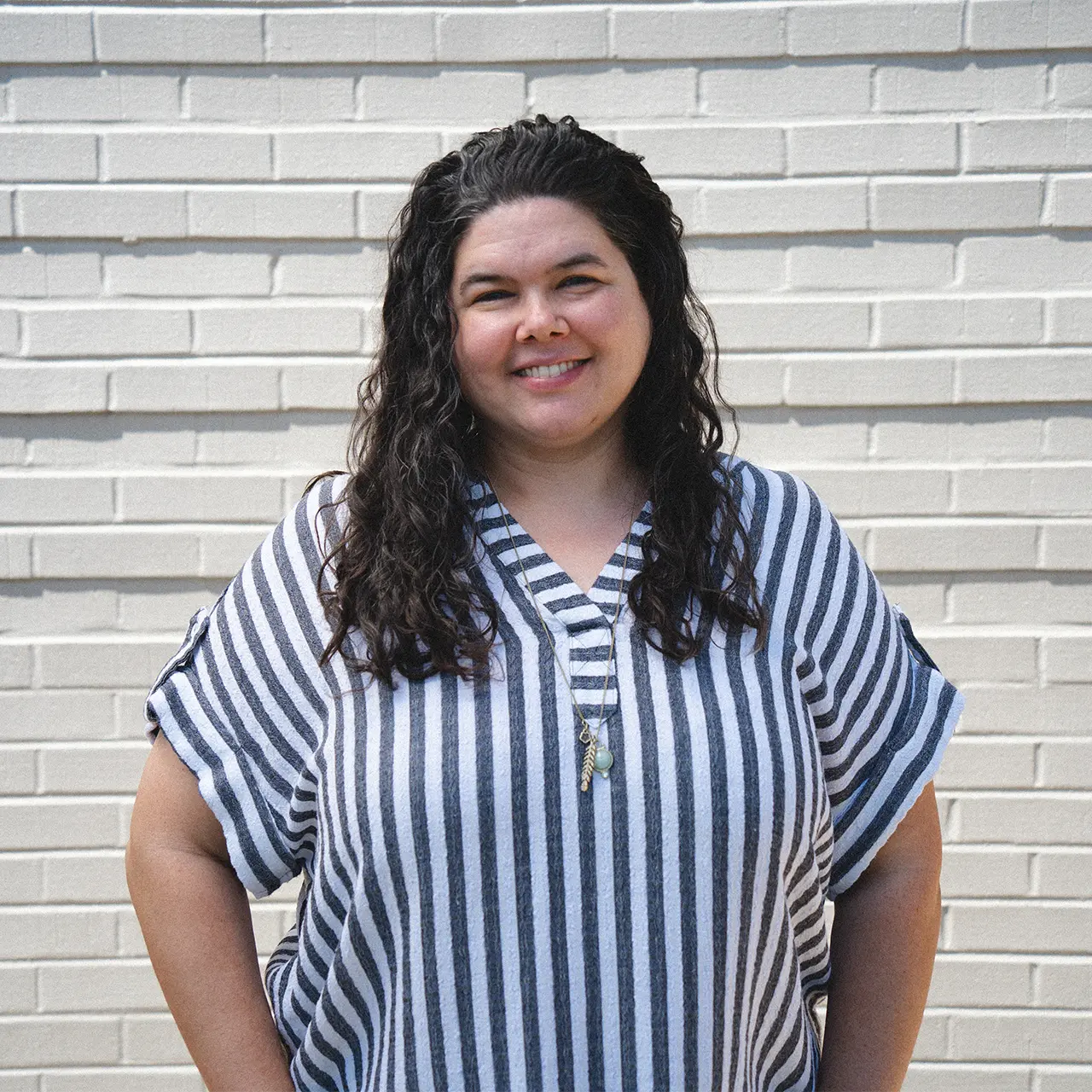 Cassie Armstrong is smiling and wearing a blue and white striped shirt.
