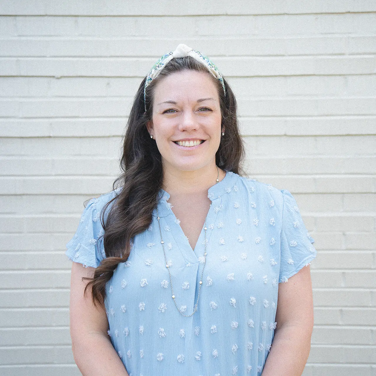 Meri Wheeler is smiling and wearing a light blue shirt with a matching headband.