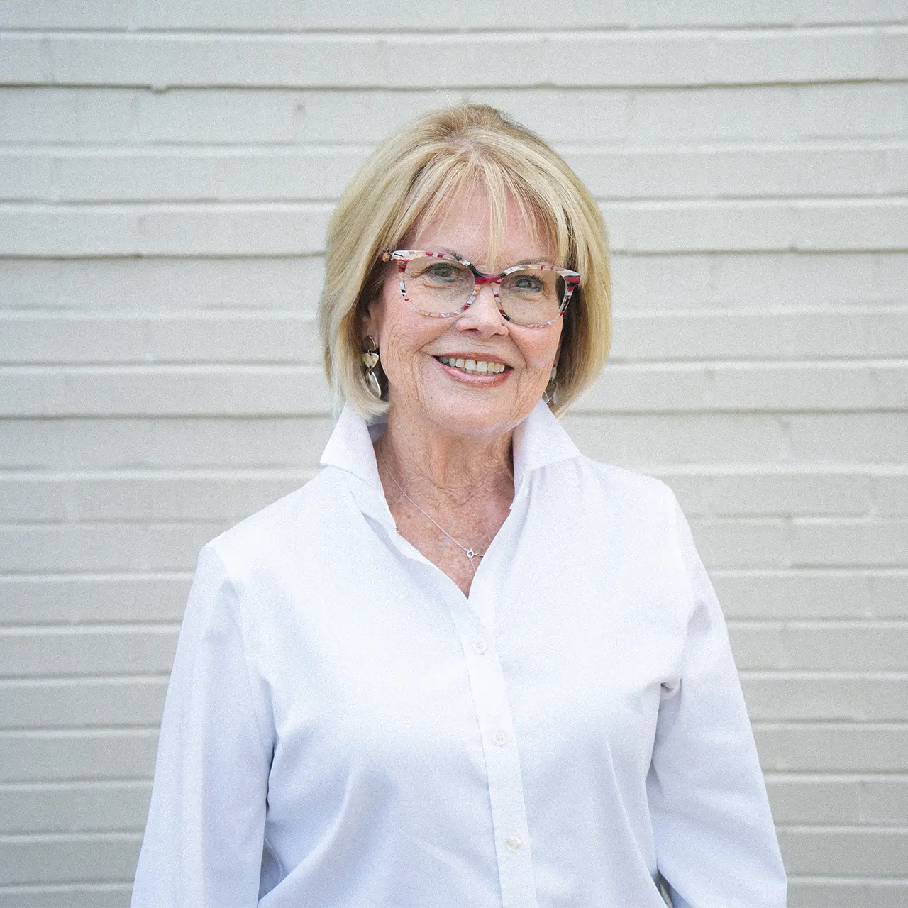 Regina Ontjes is wearing a white collared shirt and is smiling.