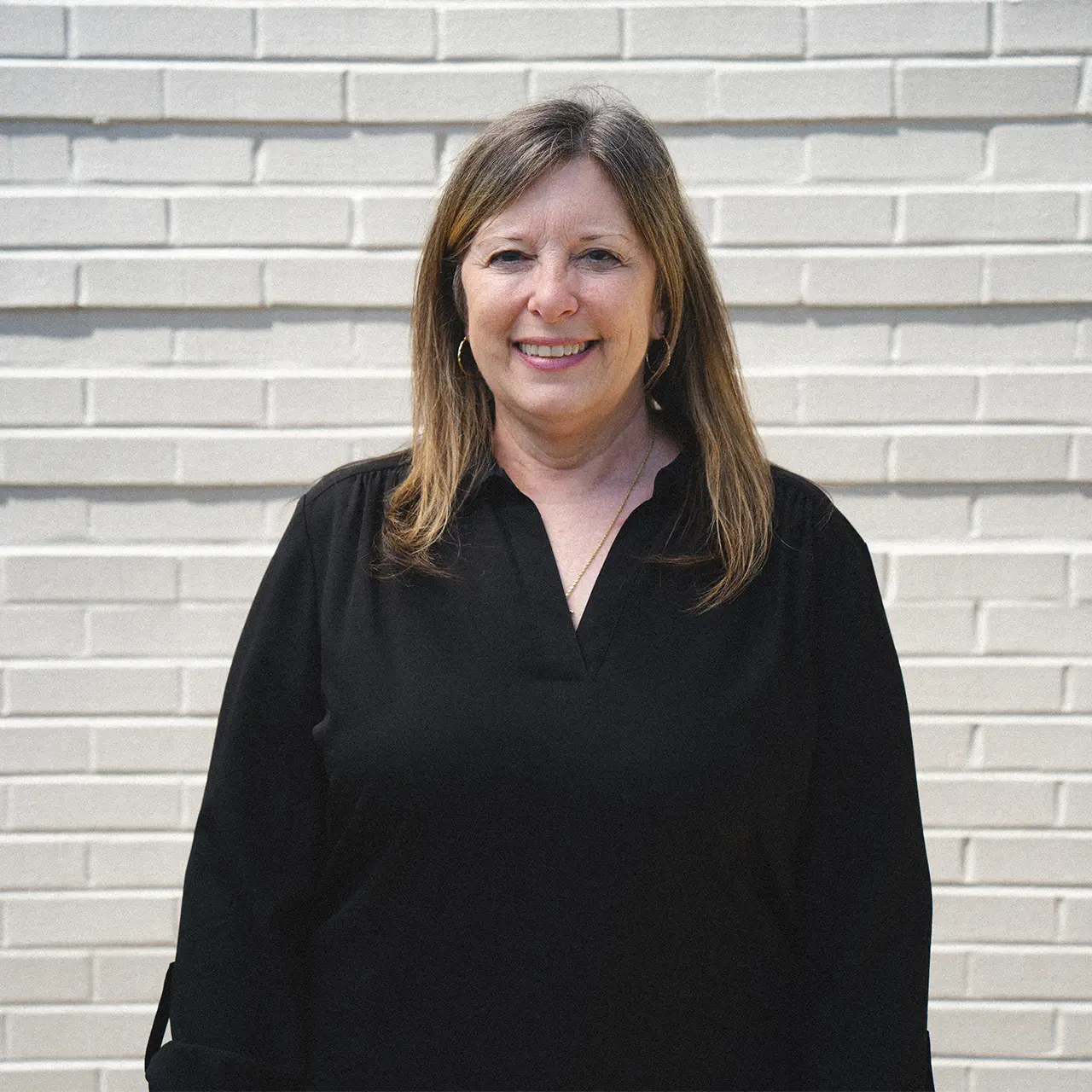 Susan Baer is wearing a black shirt and smiling.