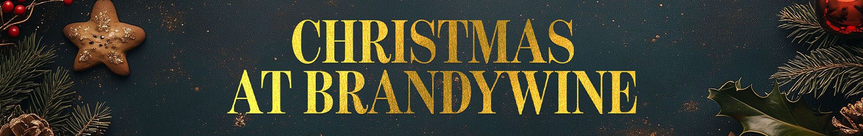 A dark grey background with gold dust scattered throughout. On the left edge are pine branches, red berries and a star-shaped gingerbread cookie. On the right edge are pine branches, a holly leaf and a red Christmas ball decoration. The gold text says: Christmas at Brandywine.